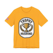 Yellow t-shirt with 'Trophy Husband' graphic design on a white background