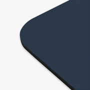 The edge of a navy blue mouse pad with a circular design featuring an eagle and text celebrating America's 250th anniversary.
