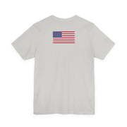 Back of a light grey t-shirt with American flag on the back against a white background