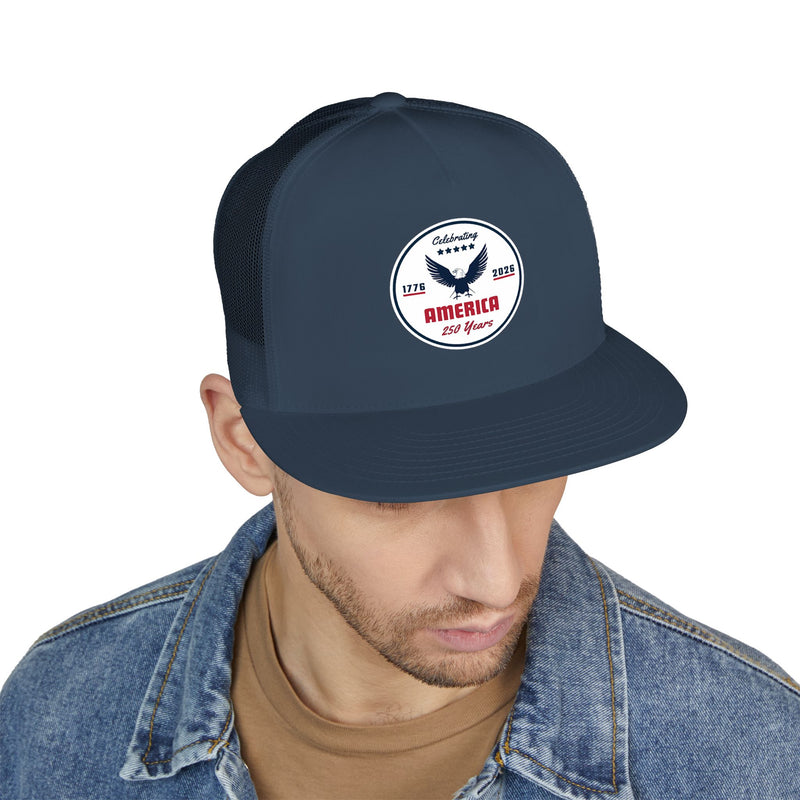 Man wearing an all navy blue flat bill trucker cap with a logo 'celebrating America 250 years' on a white background.