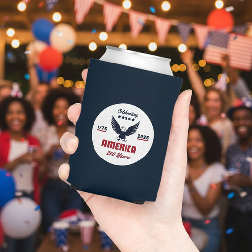 A Navy blue can cooler with a white circular design featuring an eagle and America 250 years text on a white background held in a hand with beverage in it.