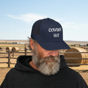 Man wearing a navy blue  trucker hat with 'Cowboy Hat' text in front of a ranch. 