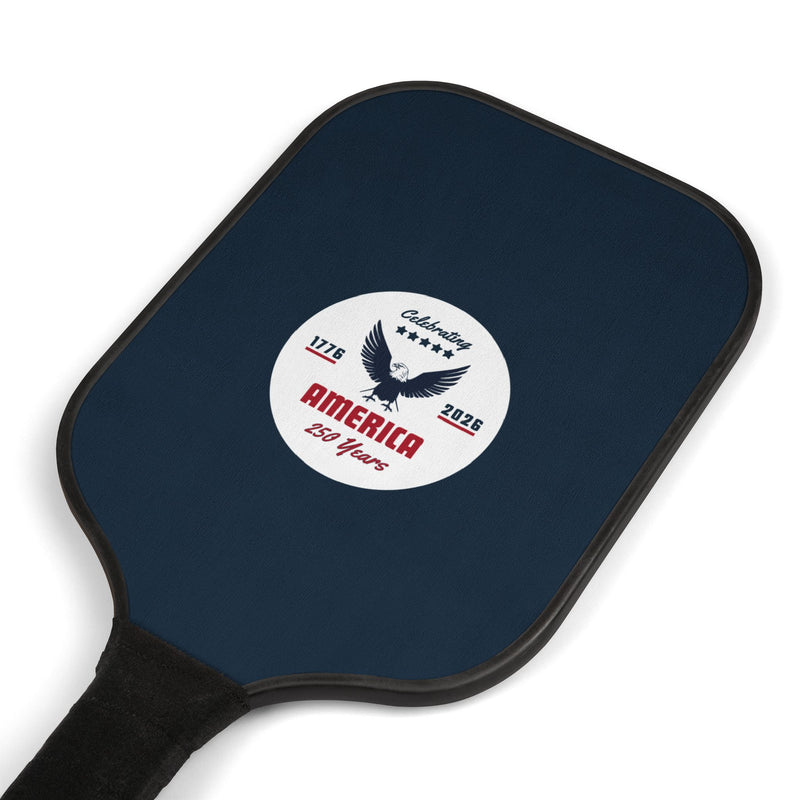 Navy blue pickleball paddle laying at an angle with a white logo that says 'Celebrating America 250 years' on a white background. 