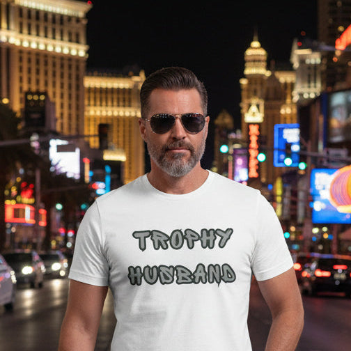 Man wearing a white t-shirt with 'Trophy Husband' text walking on street in vegas. 