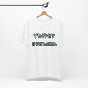 White t-shirt with 'Trophy Husband' text on a hanger against a white background