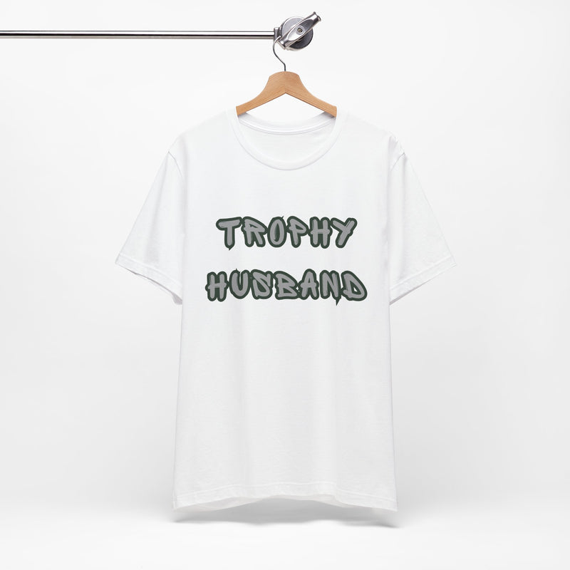 White t-shirt with 'Trophy Husband' text on a hanger against a white background
