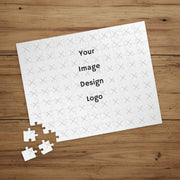 A customizable puzzle that has been put together and it marked by a "Your Image, Design or Logo here" image with the corner pieces pulled off on a wooden card table.