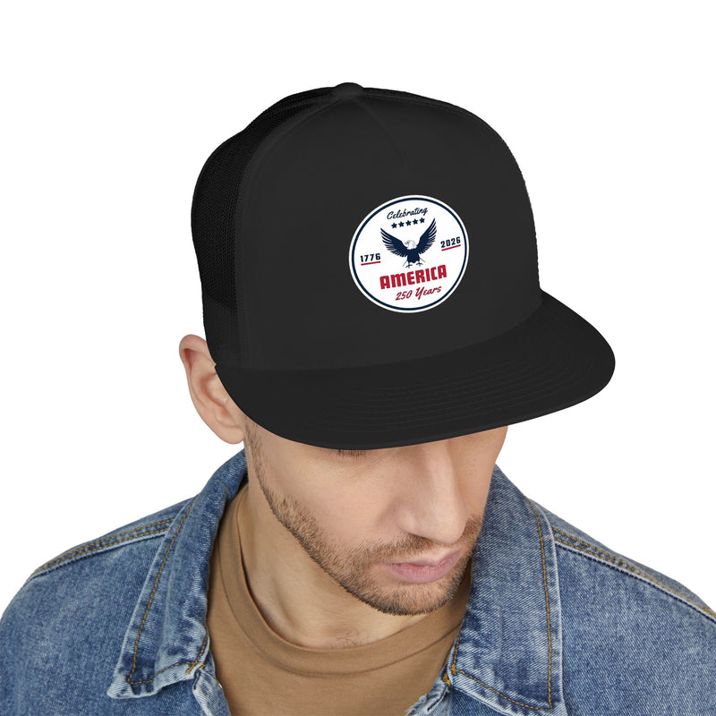 Man wearing an all black flat bill trucker cap with a logo 'celebrating America 250 years' on a white background.