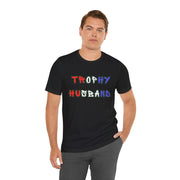 Man wearing a black t-shirt with 'Trophy Husband' in red white and blue text on a white background