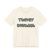 Beige t-shirt with 'Trophy Husband' text on a white background