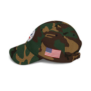 Side of camouflage classic ball cap with a circular emblem featuring an eagle and text , along with the American flag on the side on a white background.