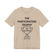 Beige t-shirt with 'The Participation Trophy 1st Place' text and graphic on a white background