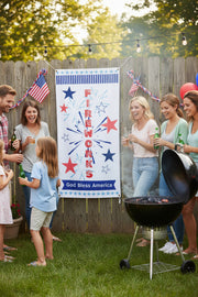 Patriotic vinyl banner with red white and blue stars, fireworks and the word fireworks 24x48 and 36x72 inches on fence at patriotic party.