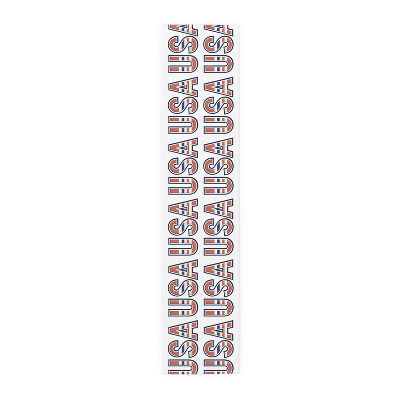 Table runner with 'USA' in red white and blue repeated on a white background. 