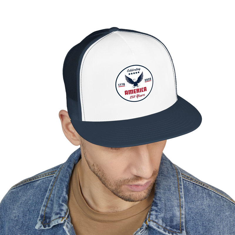 Man wearing a white and navy blue flat bill trucker cap with a logo 'celebrating America 250 years' on a white background.
