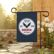 Garden flag celebrating America's 250th anniversary on a stand with flowers and stones in the background.
