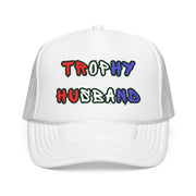 White trucker hat with 'Trophy Husband' in red white and blue text,  against a white background