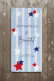 Patriotic vertical vinyl banner 24x48 and 36x72 inches with strips and red white and blue stars on a wood fence.