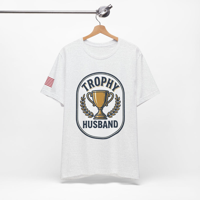 White t-shirt with 'Trophy Husband' graphic on a hanger against a white background