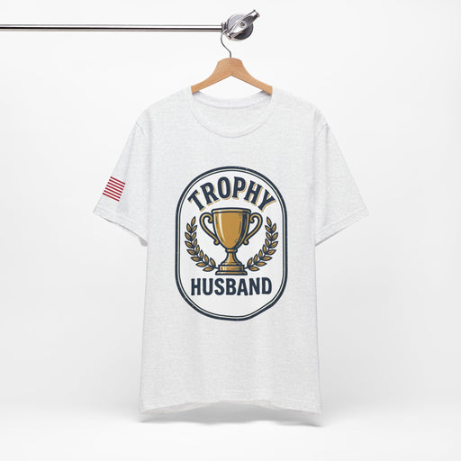 White t-shirt with 'Trophy Husband' graphic on a hanger against a white background