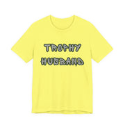 Yellow t-shirt with 'Trophy Husband' text on a white background