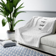 Customizable sherpa fleece blanket with "your image or design" placeholder tossed on a couch with a living room background.