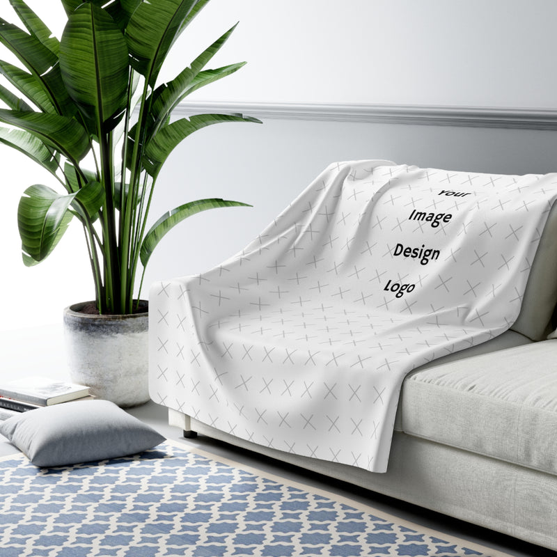 Customizable sherpa fleece blanket with "your image or design" placeholder tossed on a couch with a living room background.
