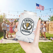 Can cooler held in a hand with 'Trophy Husband' design on a faded red white and blue firework display in front of a party. 