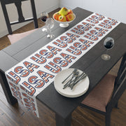 Table runner with 'USA' in red white and blue repeated displayed on a table.