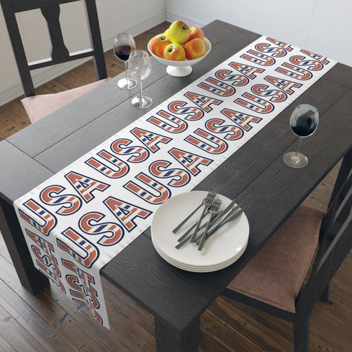 Table runner with 'USA' in red white and blue repeated displayed on a table.